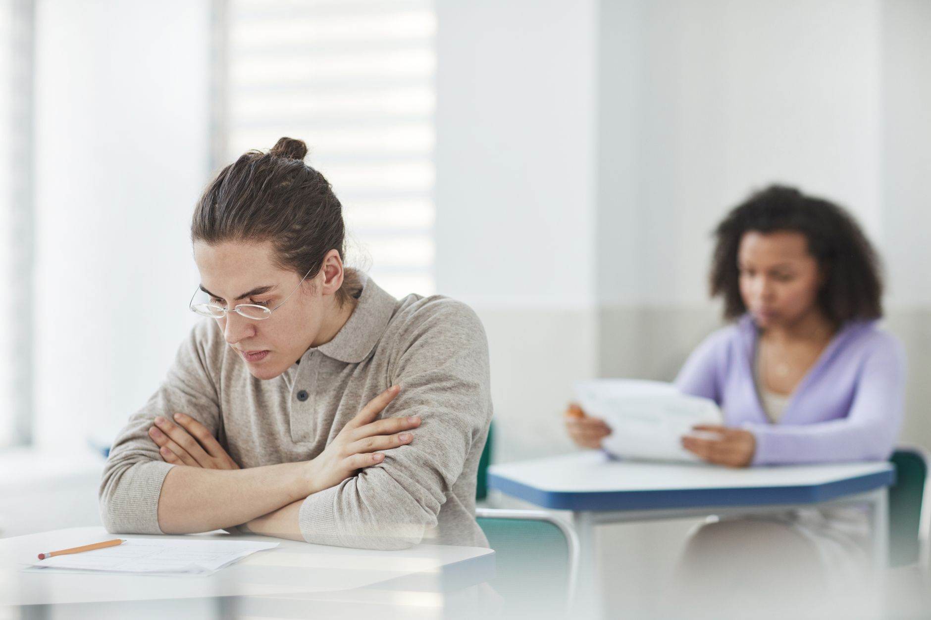 A student sitting at a desk, struggling to focus on his work