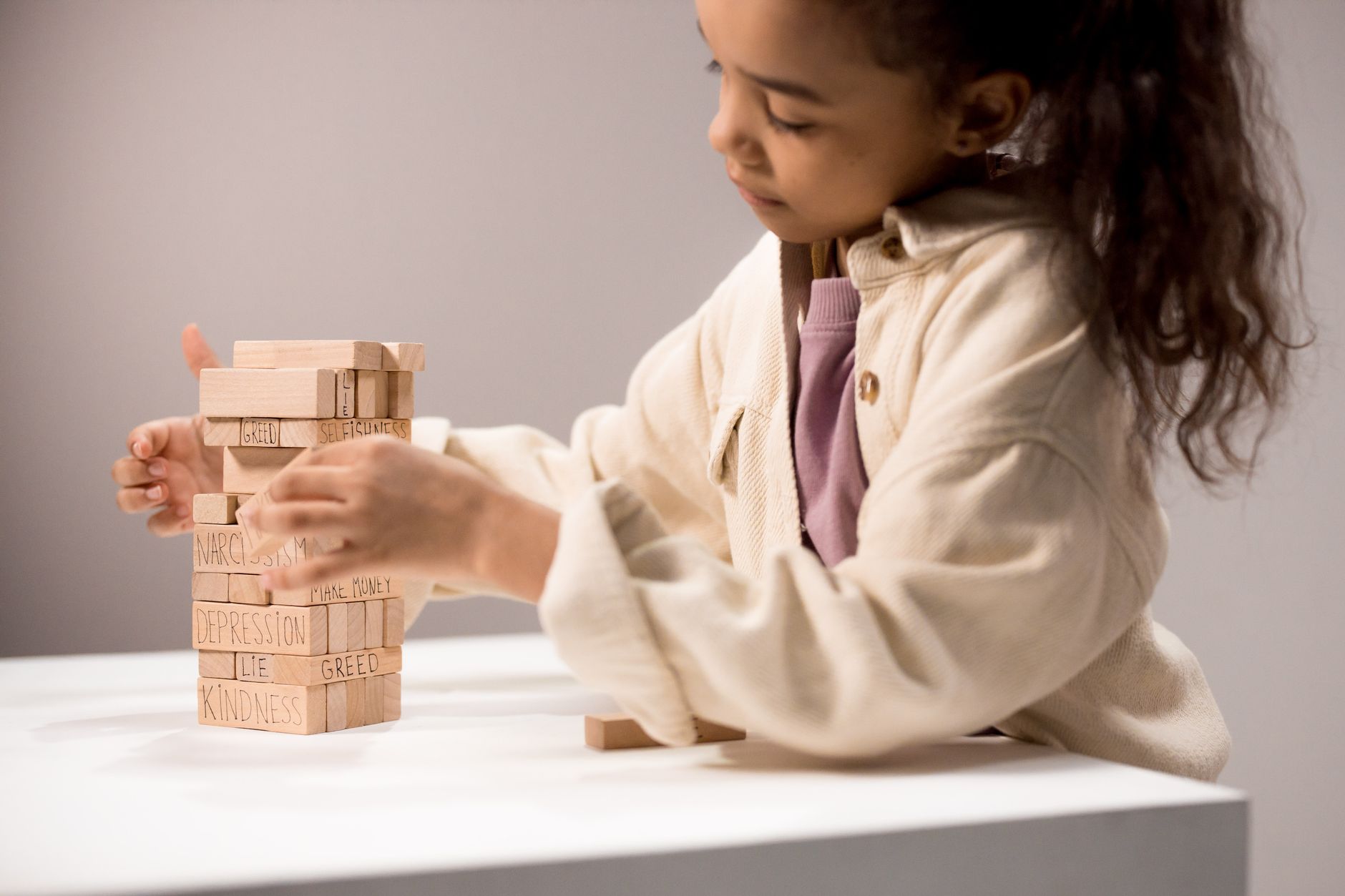 A child carefully stacking wooden blocks into a tower