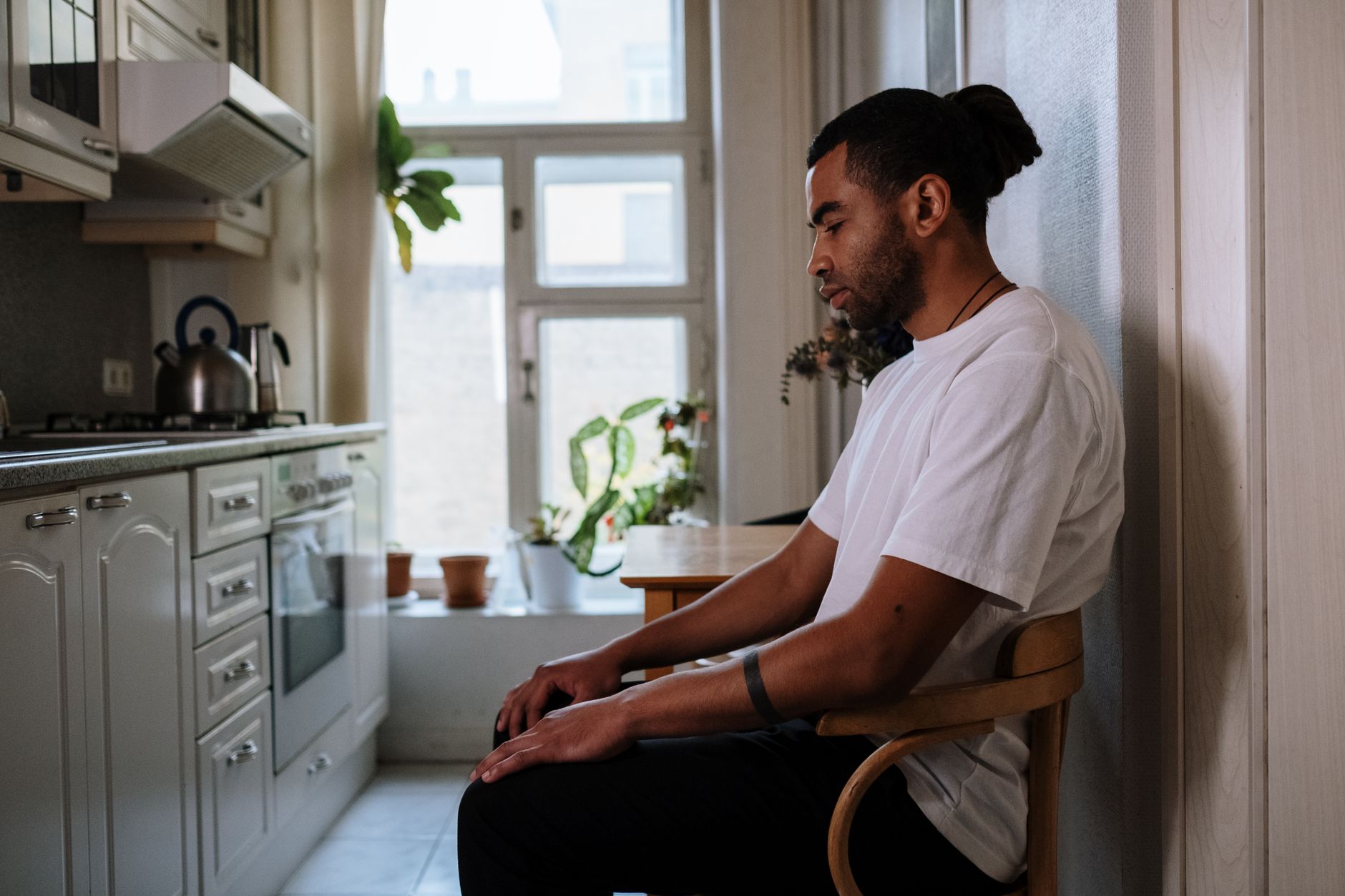 A man sitting alone at a kitchen table, looking down