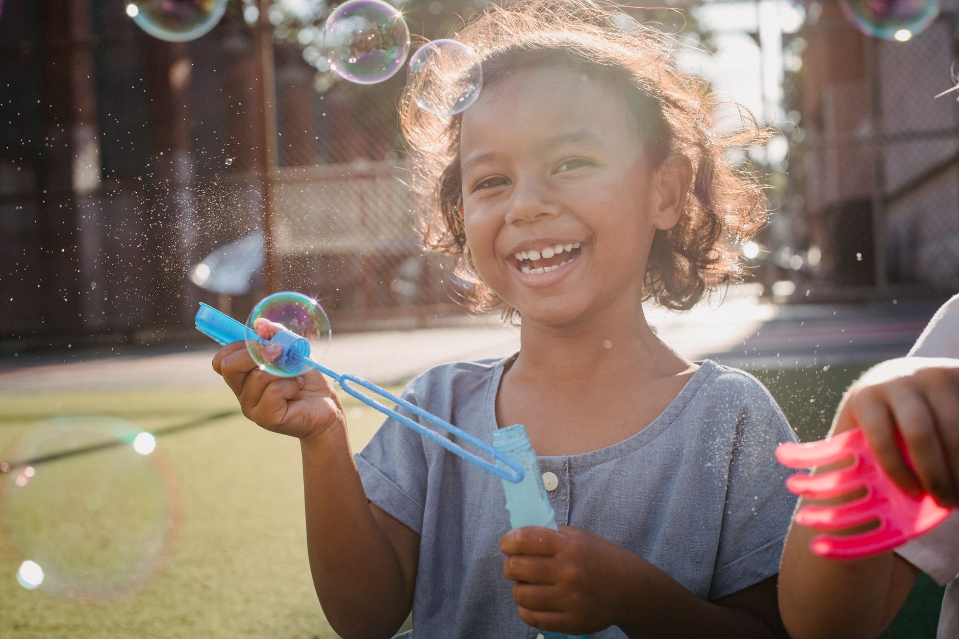 A smiling child blowing bubbles outdoors